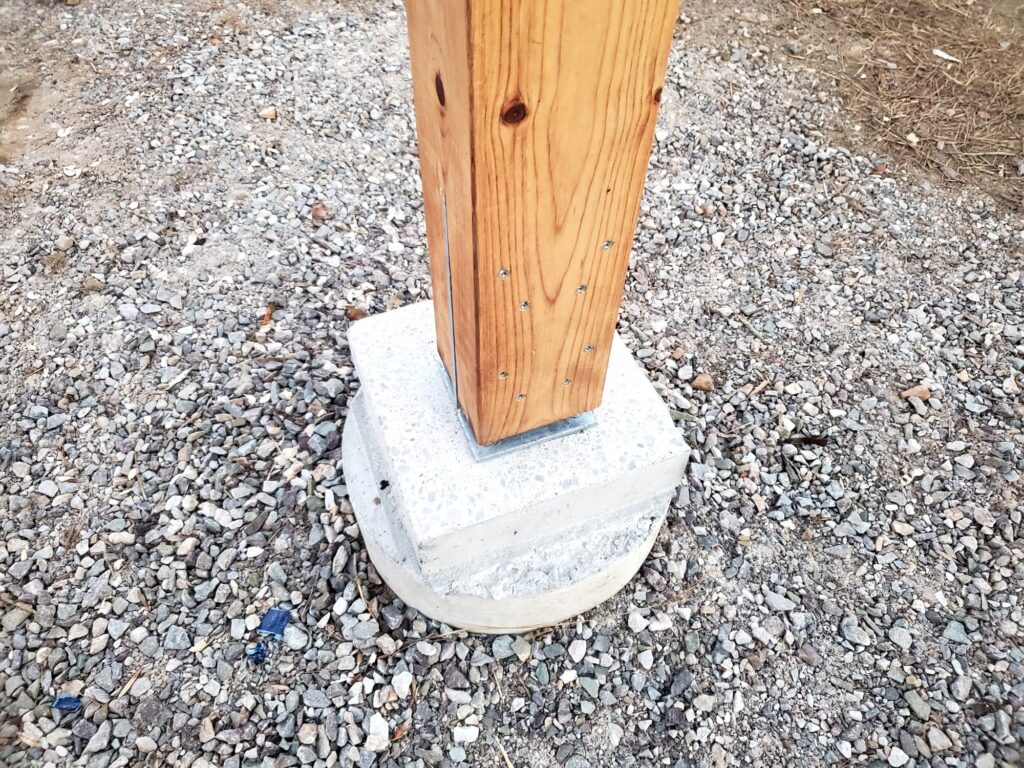 Porch post seated on its concrete pier with a metal knife plate at the base